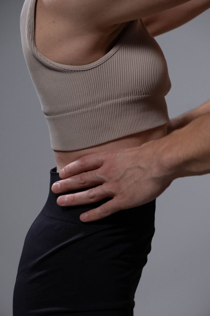 Persona con dolor lumbar y mano apoyada en la zona baja de la espalda